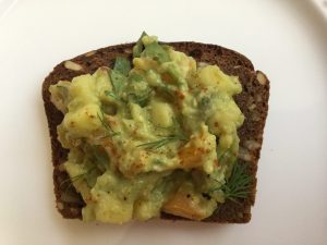 Slice of rye bread with guacamole and dill