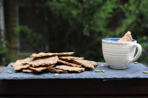 seed crackers on the tray with cup on hummus